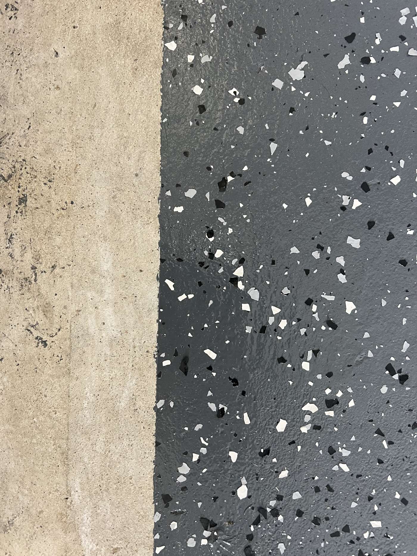 Side-by-side comparison of bare stained concrete on the left and grey flake epoxy coating on the right