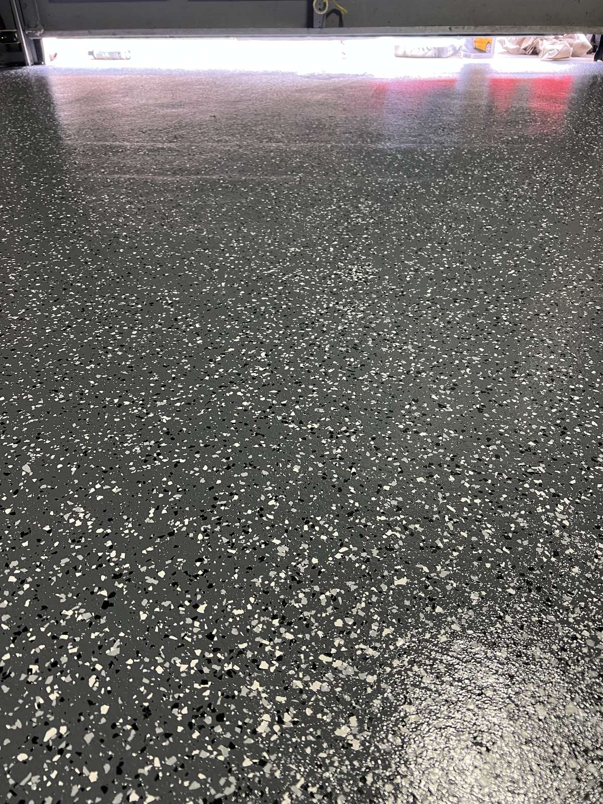 Close view of a grey flake epoxy floor with white, black and grey flakes and a glossy surface